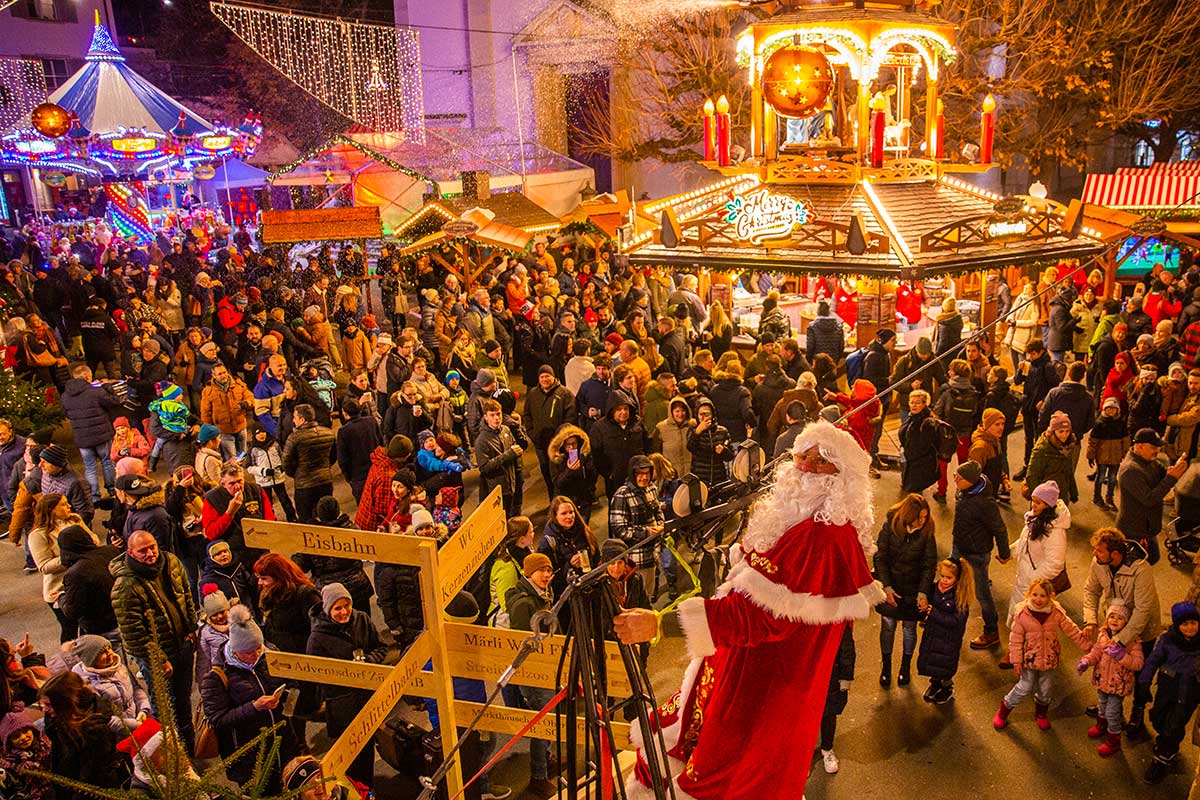 Das Adventsdorf in Olten mit dem Karussell im Hintergrund und dem Weihnachtsmann in der Menge.