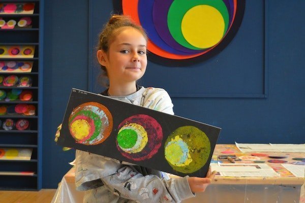 Ein Mädchen zeigt ihr Kunstwerk aus dem offenen Atelier im Kindermuseum Creaviva.