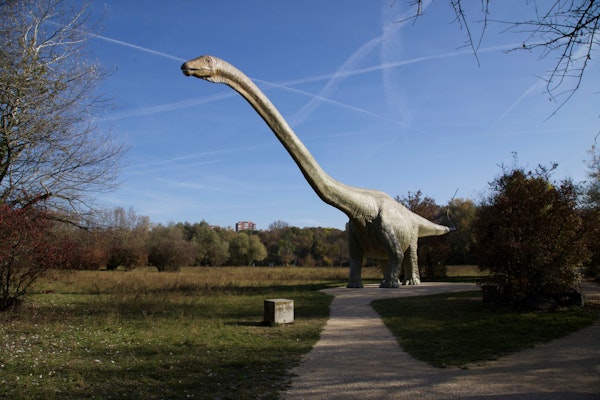 Die riesige Dinosaurier-Statue steht am Ende des Weges auf der Wiese.