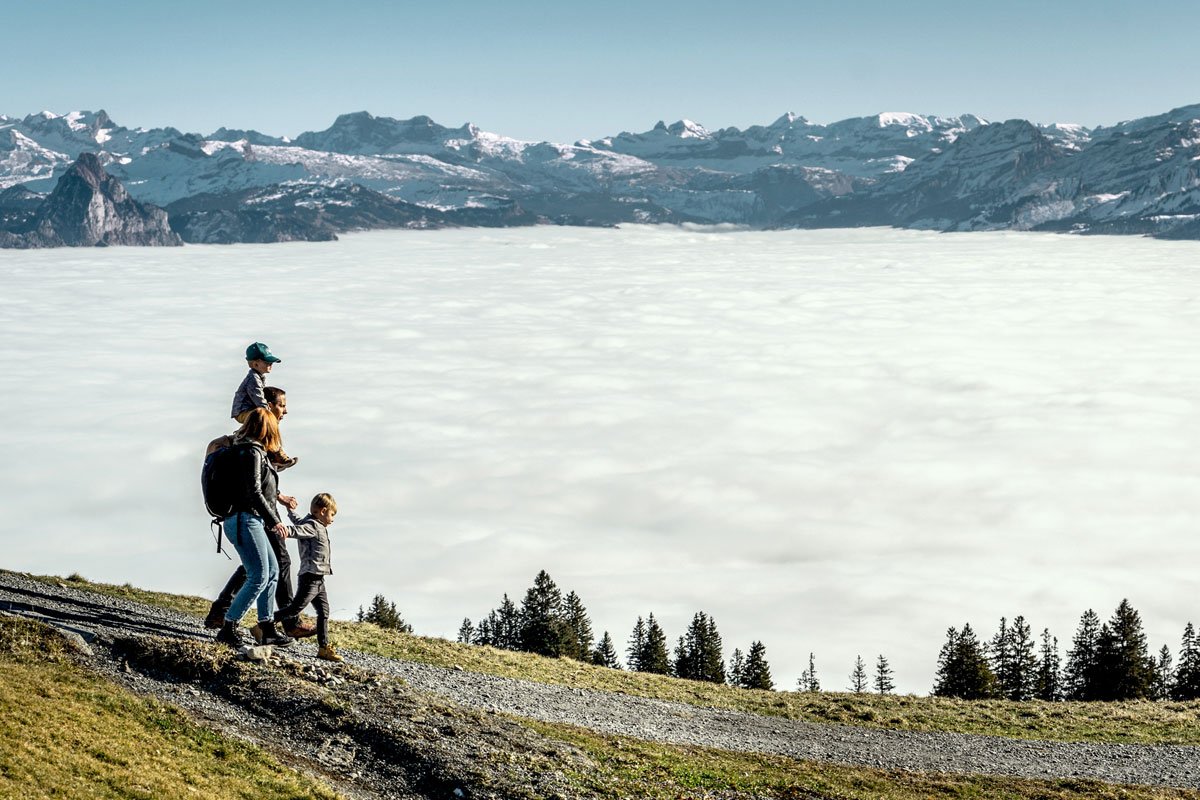 Familie wandert über dem Nebelmeer unter klarem blauen Himmel