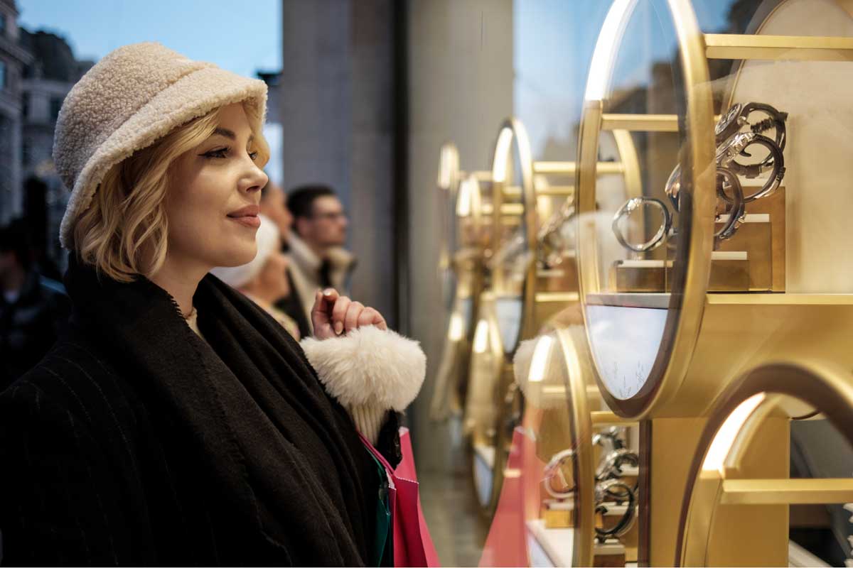 Eine junge Frau schaut in das Schaufenster einer Luxus-Uhren-Shops.