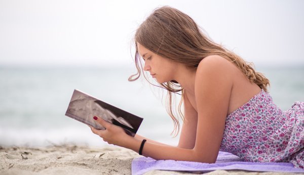 Fillette lisant sur la plage