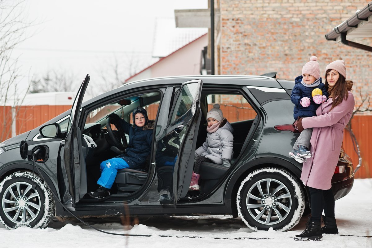 Eine Familie lädt ihr Elektroauto im Winter, um in die Winterferien zu fahren