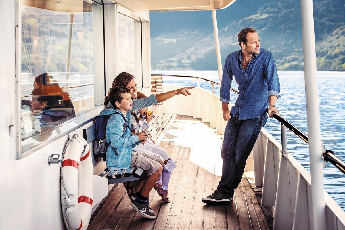 eine Familie mit Kind auf der Seite eines Schiffs schaut aufs Wasser