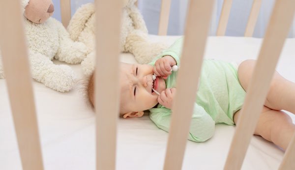 Zahnen: Baby liegt im Bett mit Beissring