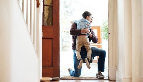 Droit de visite: le fils salue son père dans l'entrée de la maison en le serrant dans ses bras.
