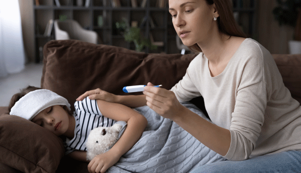 Ridurre i bambini febbre: giovane madre misura la febbre in figlia