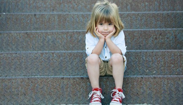 Frustriertes Kind sitzt auf einer Treppe.