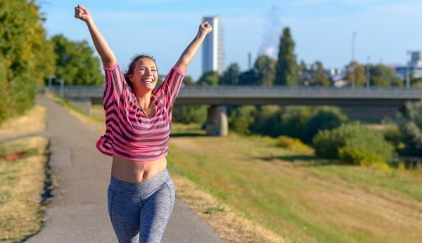 Jogging after childbirth: Mulher regozija-se, levanta as mãos no ar, jogging.