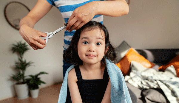 Kindern Haare schneiden: Mädchen bekommt die Haare geschnitten