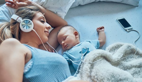 Frau mit Baby Kopfhörer Smartphone Podcast