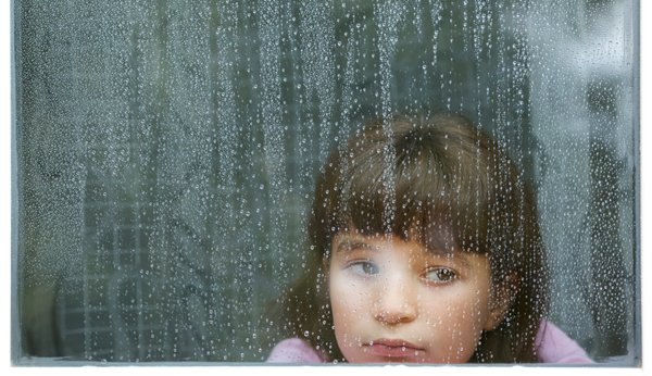 Temps pluvieux: Fille derrière une vitre pleine de gouttes de pluie