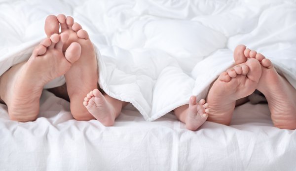 Füsse unter der Bettdecke: Vater, Baby, Mutter
