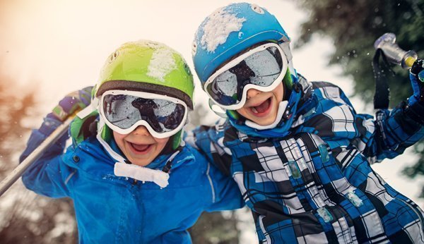 Zwei Kinder mit Skihelm - mit Helm sind Kinder sicher auf der Piste unterwegs
