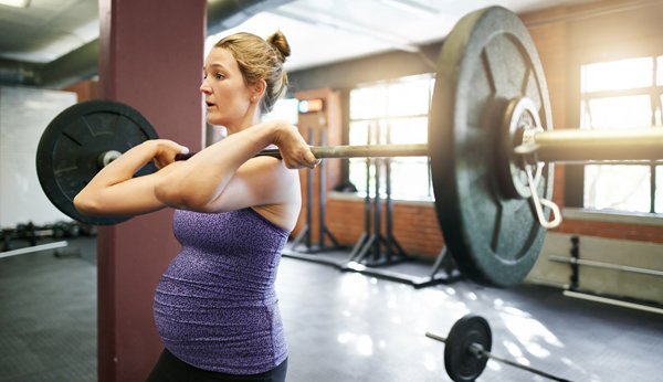 Sport in der Schwangerschaft: Schwangere Frau mit Langhantel beim Sport. 
