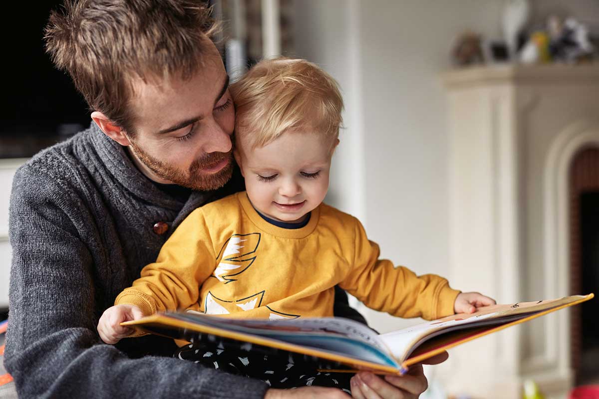 Ein Vater liest seinem Kind aus einem Kinderbuch vor.