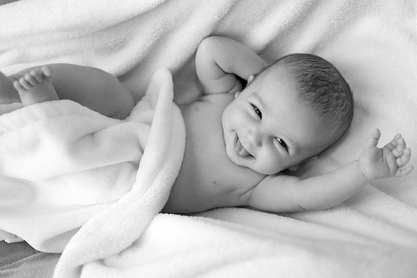 Schwarzweiss Foto eines Babys, das in ein Tuch gehüllt ist und lacht