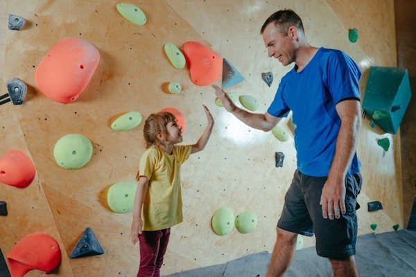Vater und Tochter geben sich in Boulderhalle ein High Five