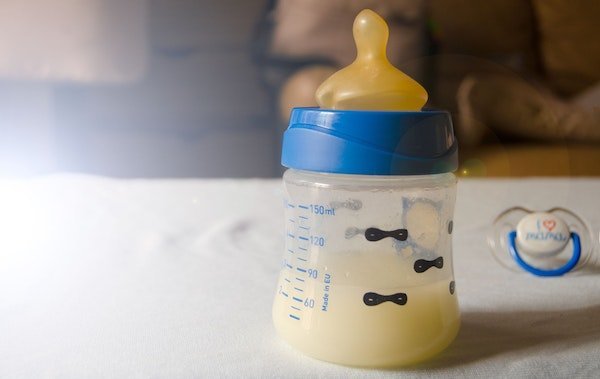 Babyflasche vor weissem Hintergrund mit gelblicher Vormilch gefüllt