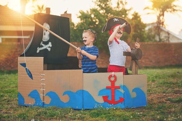 Zwei Jungen als Piraten verkleidet in einem Kartonboot