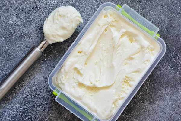Vanille, cremige Eiscreme in einem Tuberware auf einem Betongrund. Blick von oben.