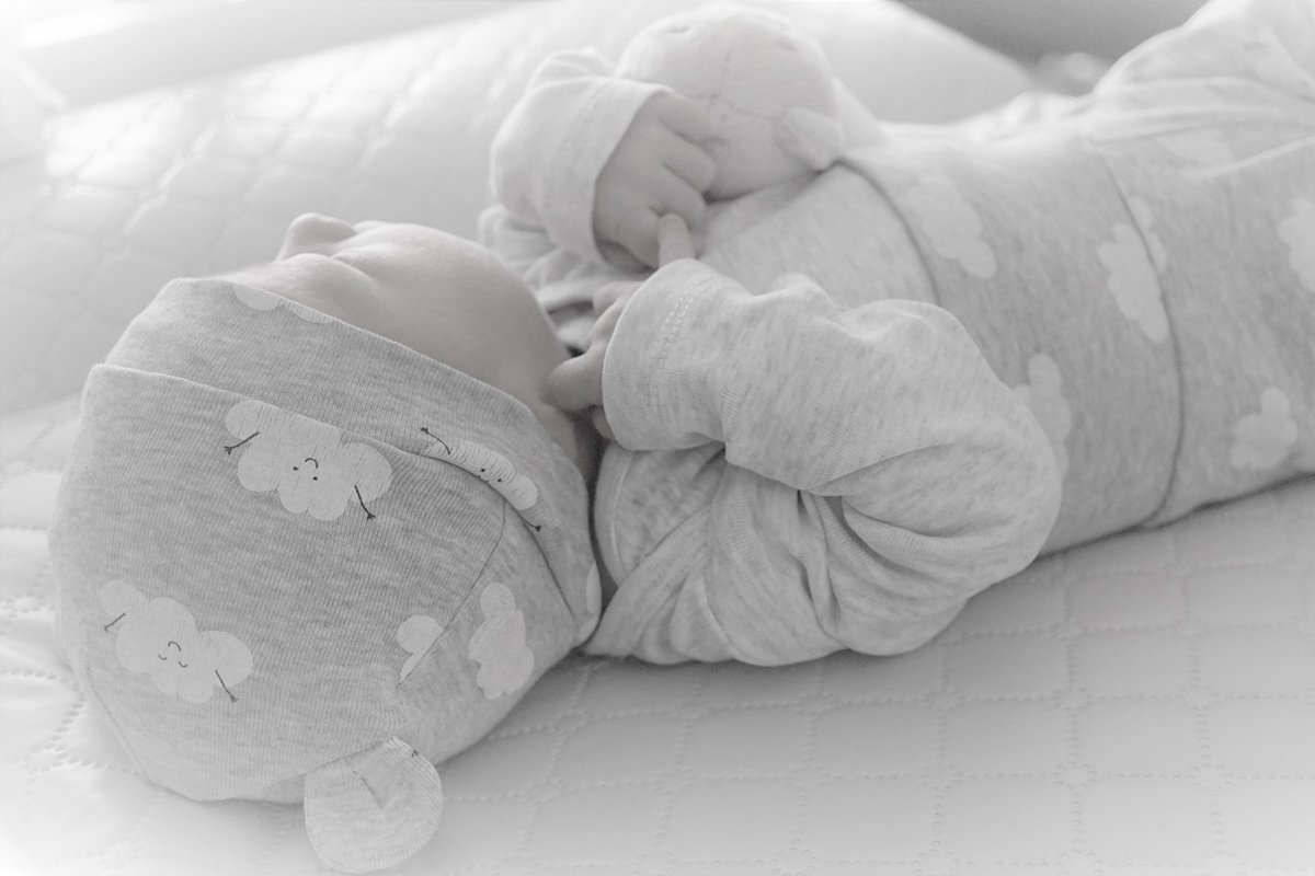 Schwarzweisses Foto eines Babys, das auf dem Rücken schläft.