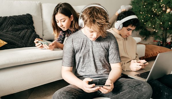 Immer nur am Handy? Drei Jugendiche sitzen auf dem Sofa und starren auf ihr Smartphone