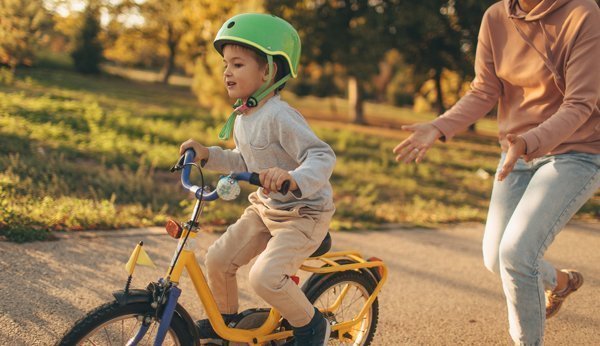 Loslassen lernen: Kind lernt Fahrrad fahren, Mutter lässt los. 