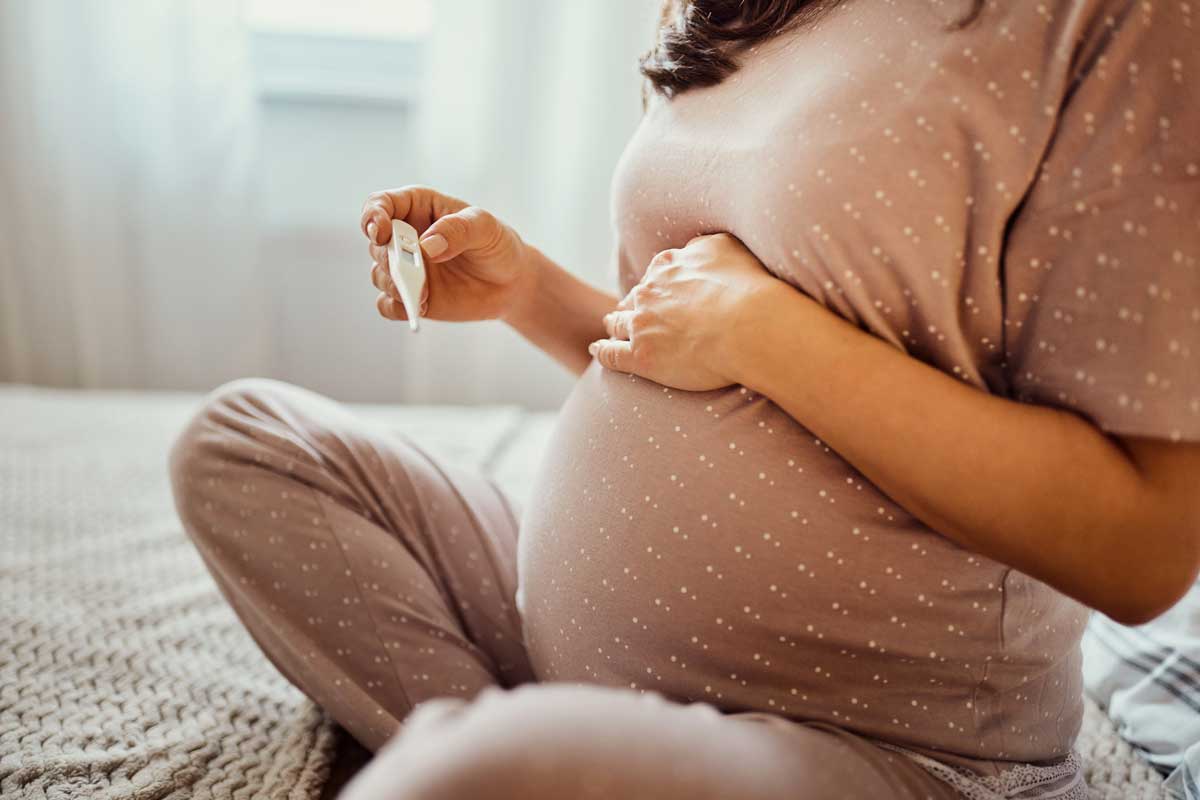 Eine schwangere Frau misst Fieber.