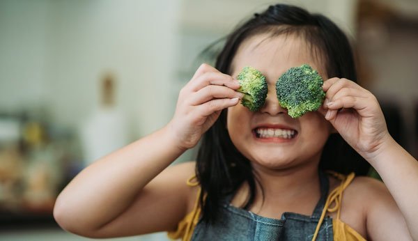 Manger sainement: Une fille tient des fleurons de brocoli devant ses yeux.