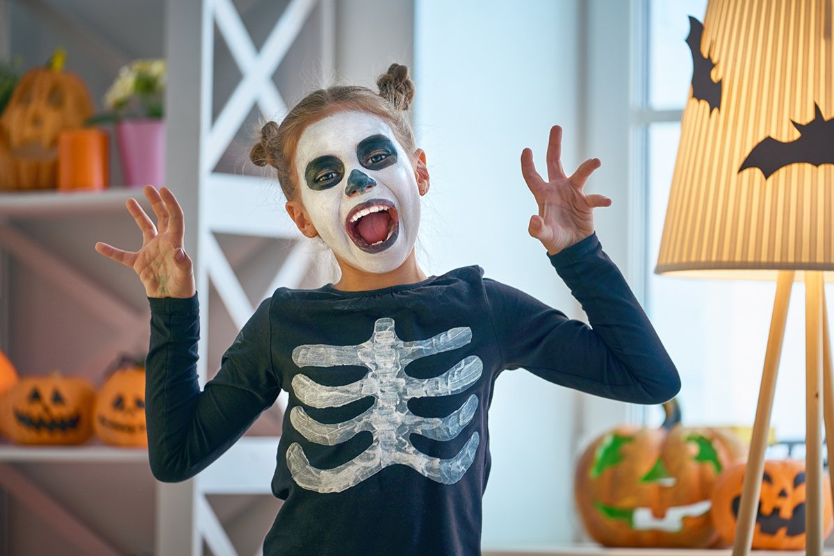 Ein Mädchen hat ein Skelett-Kostüm an und Make-up für Halloween.