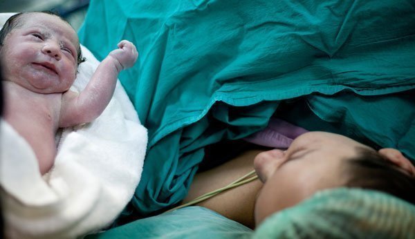 Mutter beim Bonding mit ihrem Baby im Operationssaal direkt nach dem Kaiserschnitt