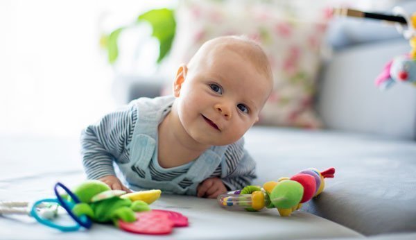 Ein Baby spielt am Boden – wie es wohl heisst?
