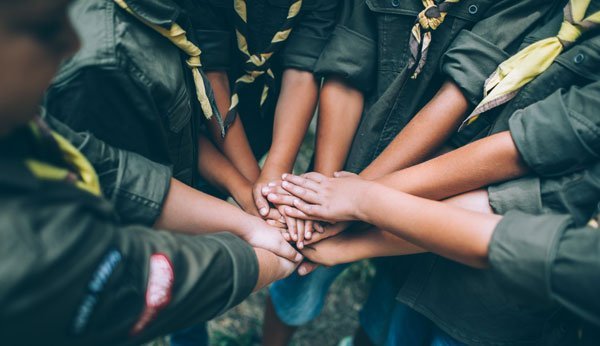 Kinder in Pfadfinder-Uniform halten die Hände in einem Kreis zusammen