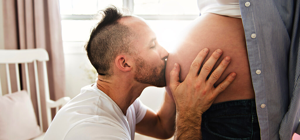 Vater küsst schwangeren Bauch der Mutter