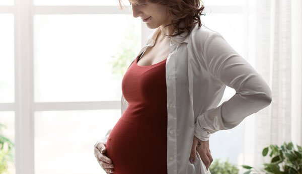 Dores de afundamento: Uma mulher grávida segura a sua barriga.