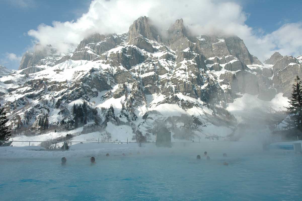Anstatt Skifahren geniesst eine Familie das Thermalbad in Leukerbad mit Bergpanorama.