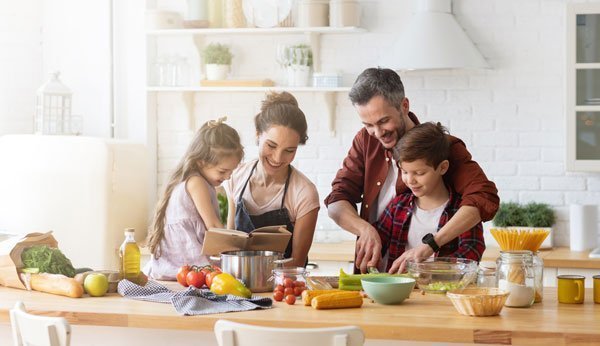 Wochenplan fürs Essen: Eine Familie mit Kindern steht gemeinsam in der Küche.